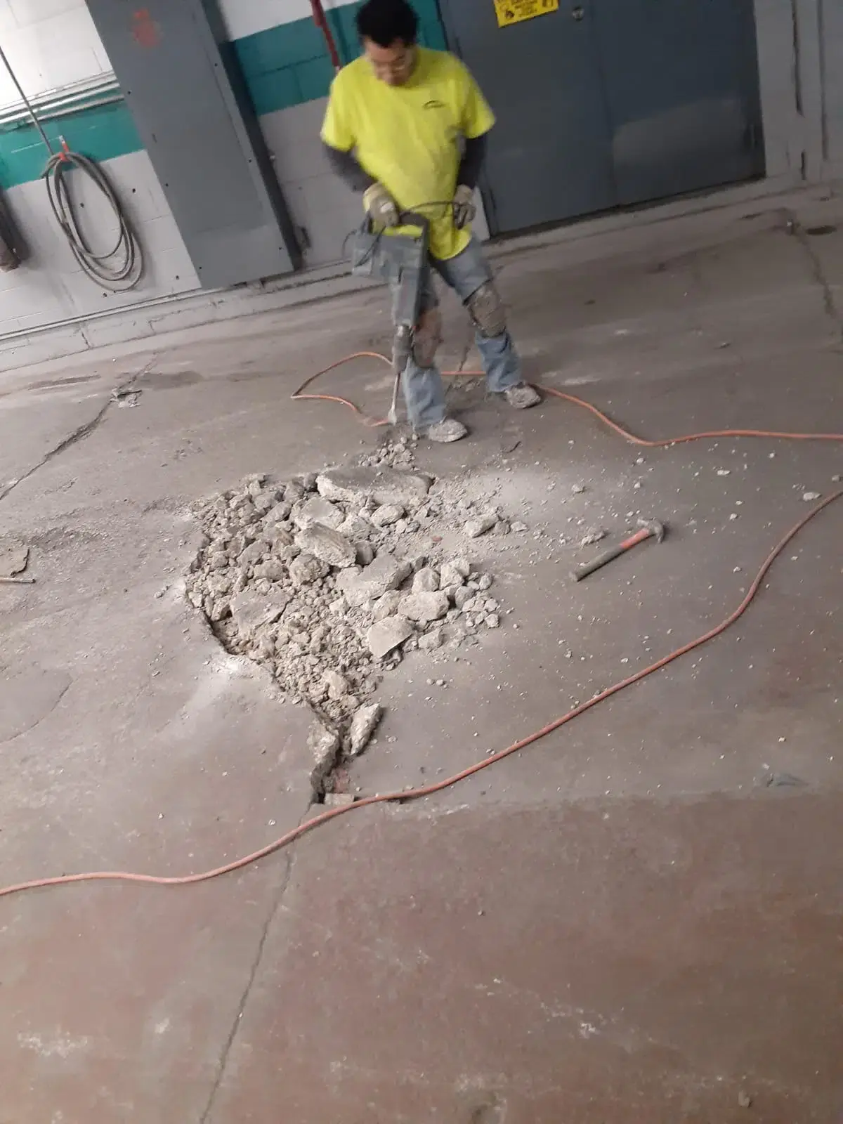 customcrete worker uses a jackhammer to prepare a floor for treatment