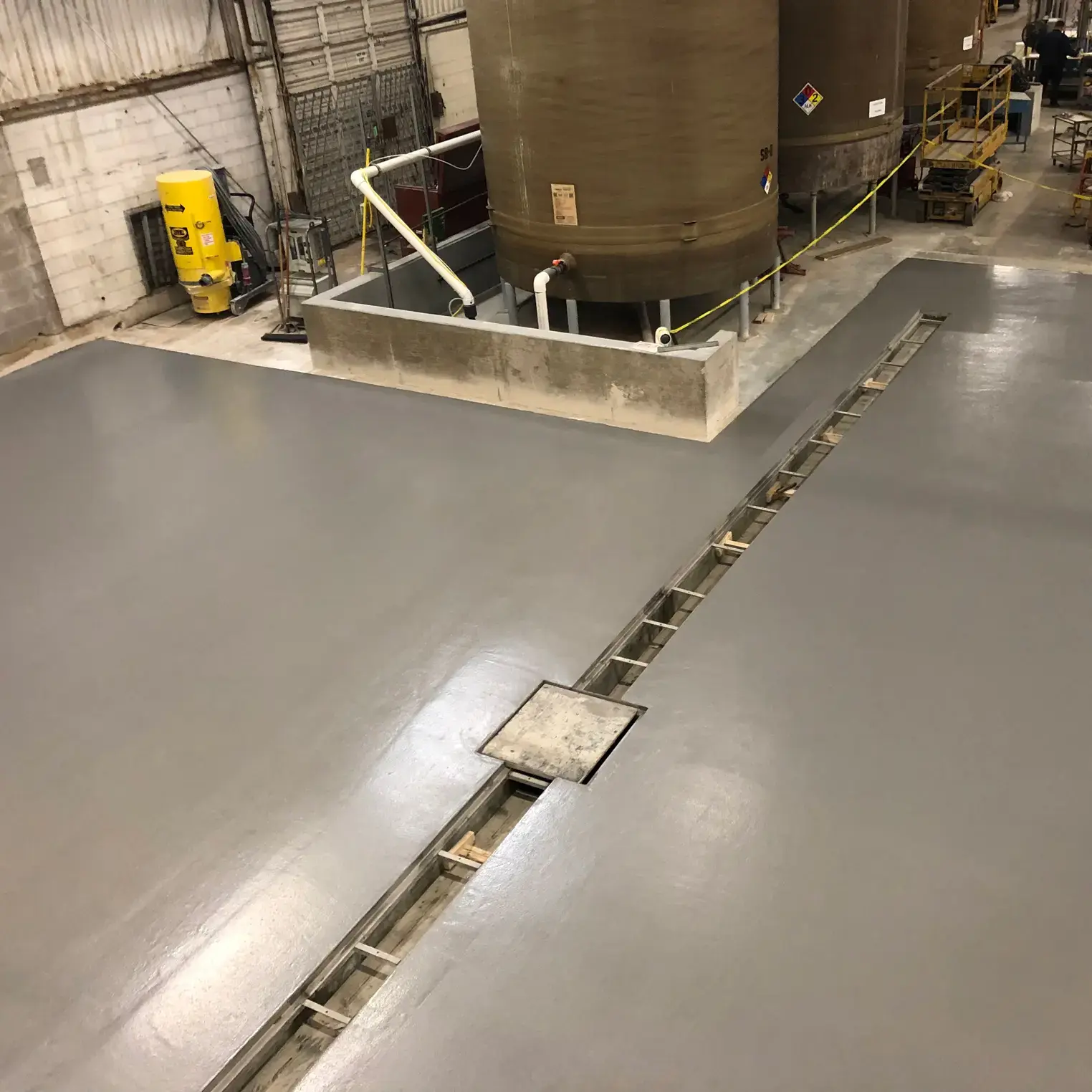 grey Urethane Cement floor with drainage in a food plant with large storage drums.
