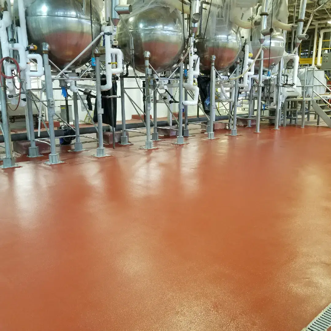 red textured urethane Cement flooring in a food plant/ brewery with large fermentation tanks in backgorund