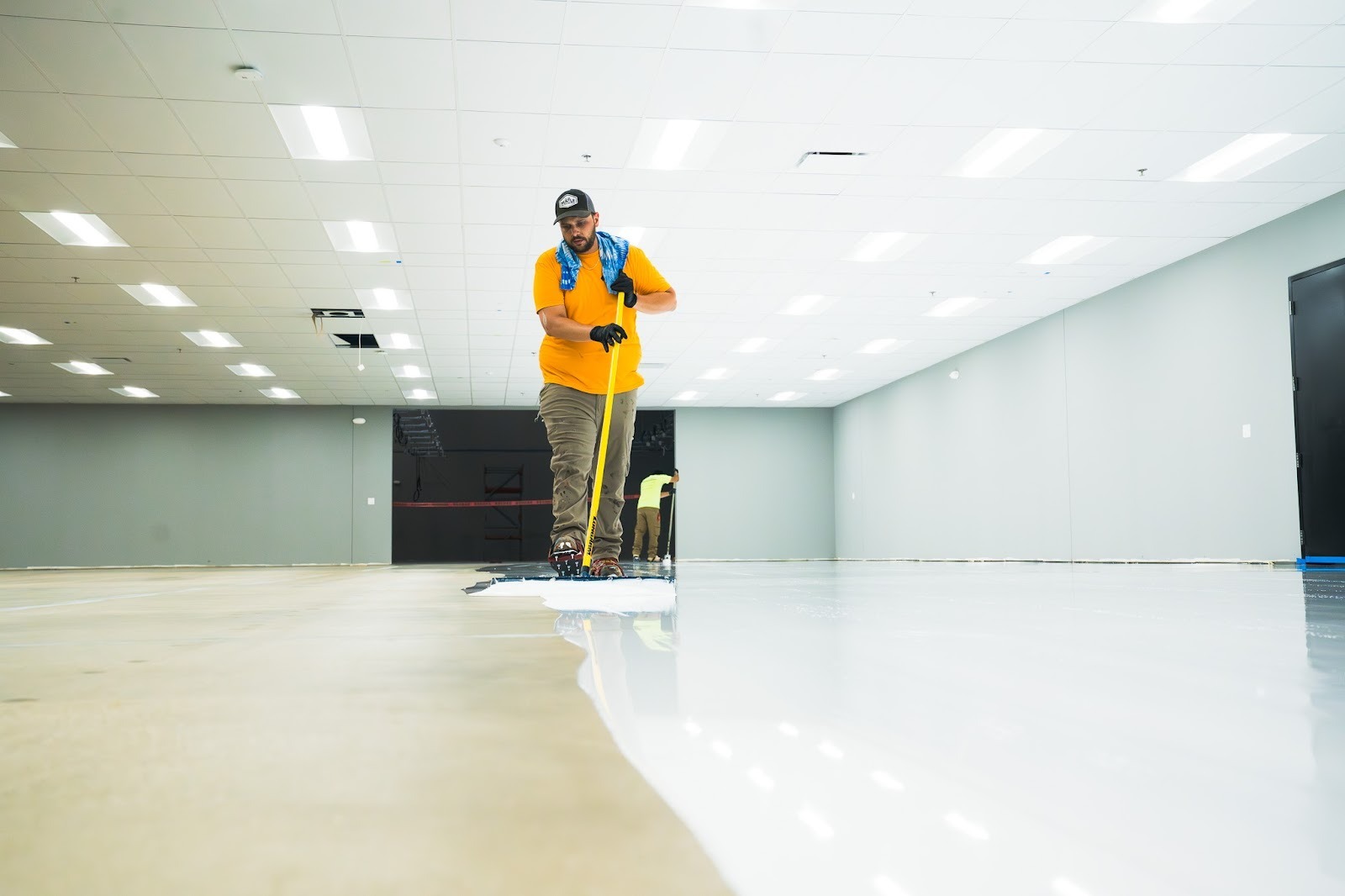 A person installing epoxy system to concrete flooring